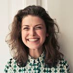 Portrait of a joyful brunette woman with a vibrant smile indoors, capturing happiness and positivity.
